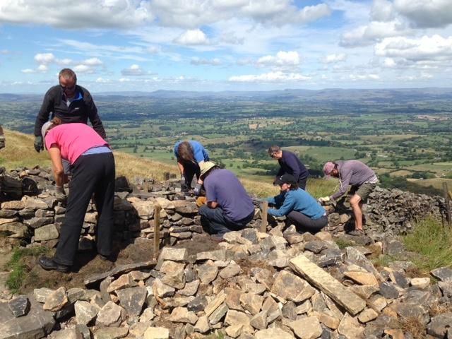 group of people rebuilding dry stone wall