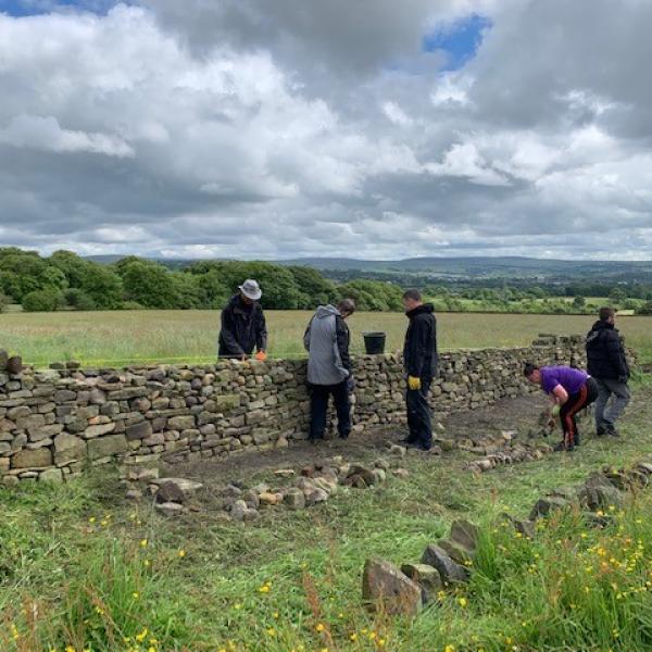 group of people rebuilding dry stone wall