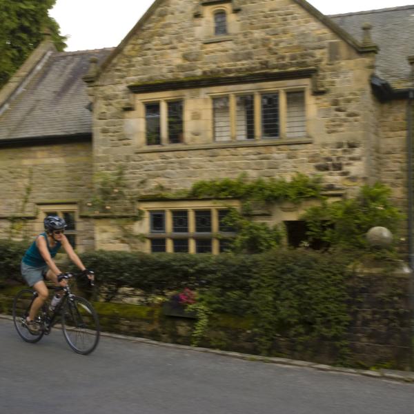 cyclist riding past a historic house